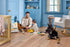 Man and baby playing with a toy truck and a dog sitting nearby in a nursery with COREtec Sand Dollar Oak flooring.