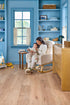Woman reading to a child in a blue nursery with 9" wide, COREtec Originals Premium, Sand Dollar Oak LVP flooring.