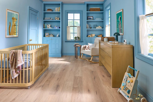 Nursery room with COREtec Sand Dollar Oak, COREtec flooring with blue walls, wooden crib, and furniture.