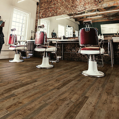 Barber shop interior with vintage-style chairs and brick wall with COREtec Duxbury Oak flooring from the COREtec Pro collection installed.